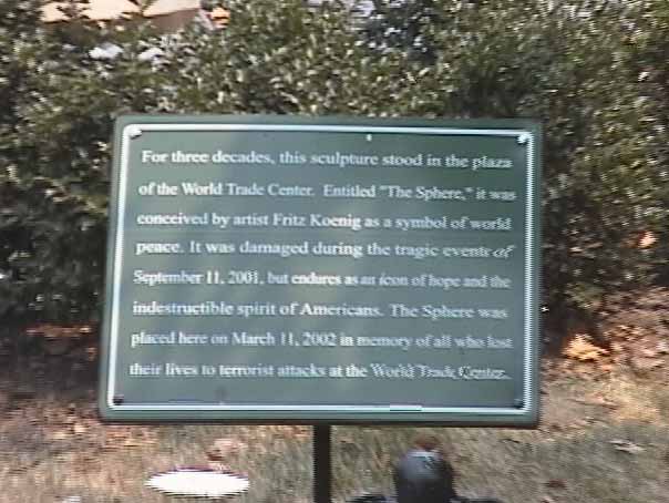 The plaque says: "For three decades, this sculpture stood in the plaza of the World Trade Center...The Sphere was placed here...in memory of all who lost their lives to terrorist attacks at the World Trade Center."